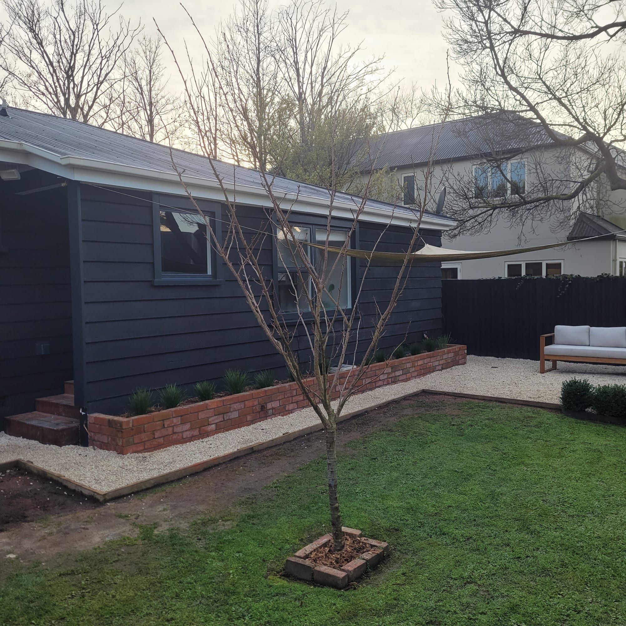 Charcoal weatherboard home with a landscaped garden